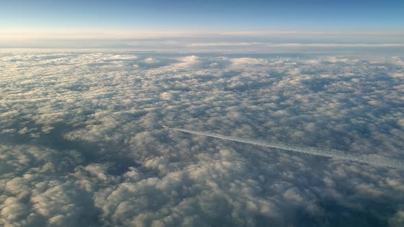 Incredible view from the cockpit of an airplane flying high above the clouds leaving a long white co alt