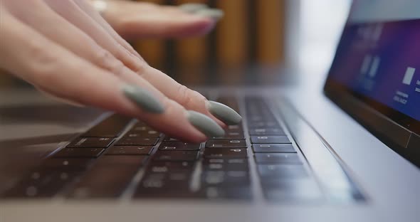 Closeup of Female Fingers with Manicure Typing Text on Laptop Keyboard alt