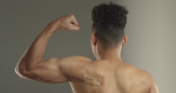 Closeup Rear View of Africanamerican Sportsman Standing Shirtless Flexing Biceps Showing Muscles alt