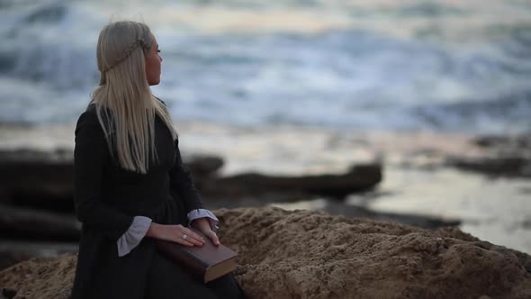 The Romantic Young Beautiful Lady Looks at Sunset with a Book in Her Hand Outdoors