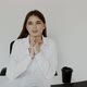 Happy Girl Talking with Gestures at Camera When Sitting at Workplace in Office