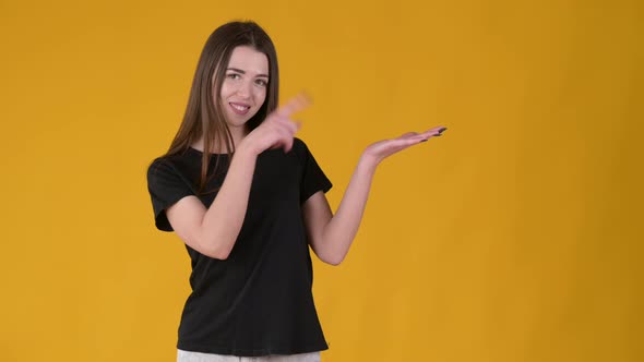 Young Happy girl with long hair in a black T-shirt pointing empty place on her palm