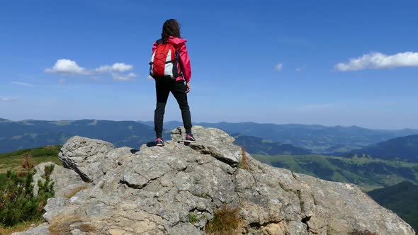 Girl on Top of the Mountain with a Backpack. Rejoice at Achievement