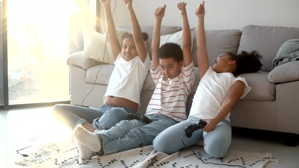 Happy African American Kids Playing Video Game with Joystick at Home alt