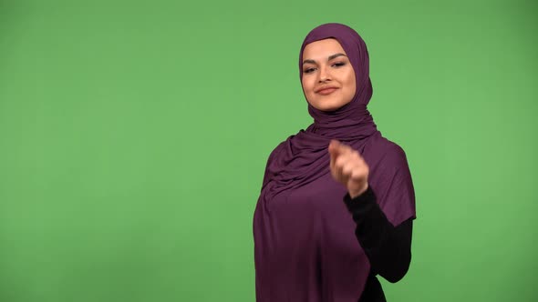 A Young Beautiful Muslim Woman Points at the Camera and Nods with a Smile  Green Screen Background