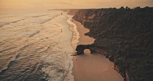 Slow Motion Sunset Ocean Seascape Waves at Rock Wall on Sand Beach Aerial alt