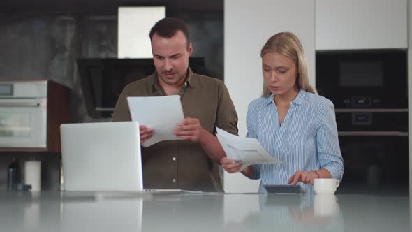 Serious Young Couple Pay Bills Online on Website App Doing Paperwork in Kitchen alt