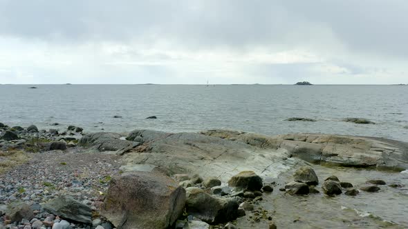 Aerial, low, view between trees, over the rocky coast of a island, in the archipelago of Porvoo, on alt