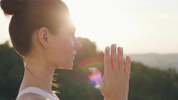 Close Up Portrait in Profile of Beautiful Yoga Woman Doing Namaste on Hill
