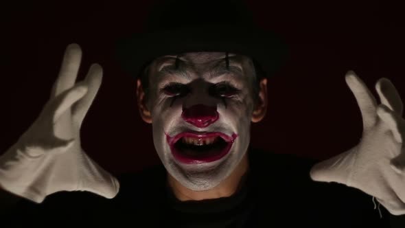 Terrible Clown Looks at the Camera and Laughs Terribly. A Terrible Man in a Clown Makeup Waves His