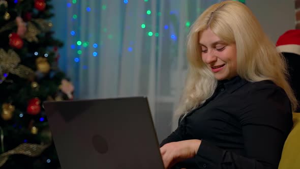 Female person sitting on couch using laptop at home. Attractive 30s woman looking at screen notebook alt