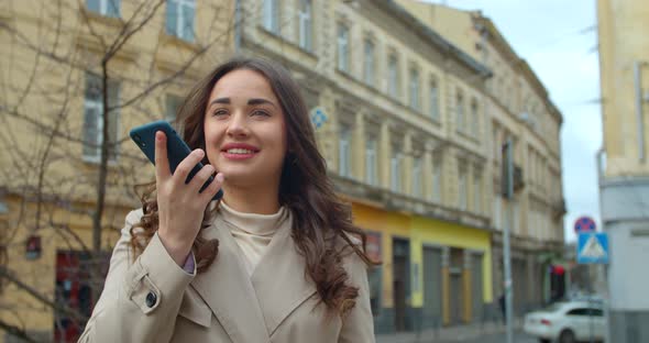 Woman Using a Smartphone Voice Recording Function Online in the City Street, Voice Message. Girl alt