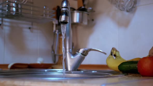 Female Hands Washing a Cucumber Apple Bananas with Running Water From the Tap alt