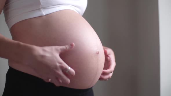 Close-up of pregnant woman rubbing her bare stomach