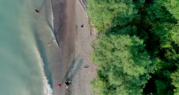 Overhead Aerial Shot of a lakeshore with various people along the shore enjoying a hot summer day wi alt