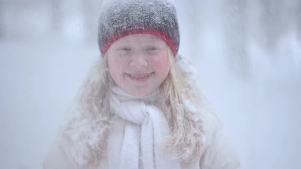 Portrait of a Beautiful Blonde Girl in the Winter Forest with Falling Snow