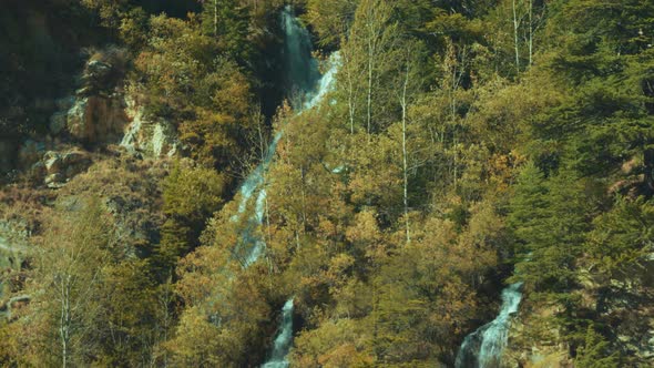 Natural Waterfall in Himalayas Surrounded by green trees seen from Uttarkashi-Gangotri Highway Road