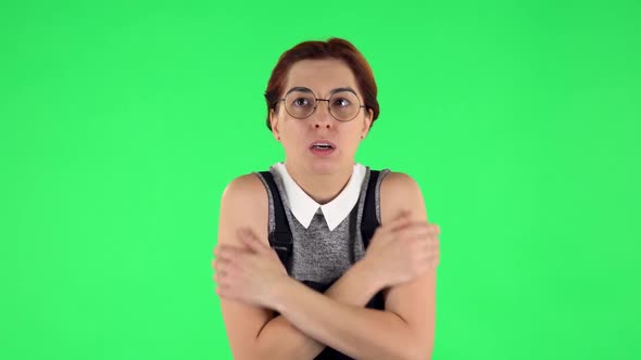 Portrait of Funny Girl in Round Glasses Froze and Trying To Keep Warm. Green Screen alt