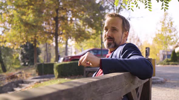 A Middleaged Handsome Caucasian Man Thinks About Something As He Sits on a Bench