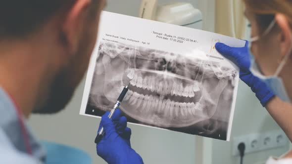 Female Doctor Shows the Patient an Xray of the Teeth alt