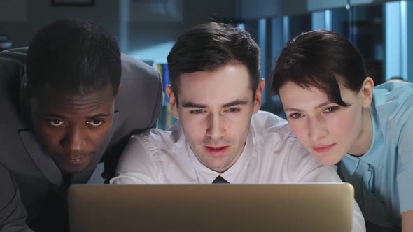 Close Up of Multiethnic Colleagues Looking at Laptop Screen and Discuss Smiling Working Late alt