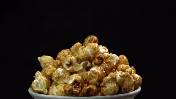 Coffee taste popcorns rotating into the bowl on black background close up. Caramel popcorn. Health alt