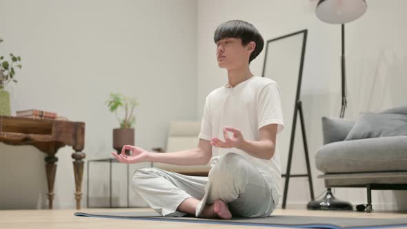 Young Asian Man Meditating on Yoga Mat at Home alt