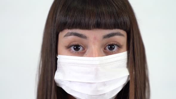 A young girl with protective mask  look at camera. Coronavirus icon. Close up shot. alt