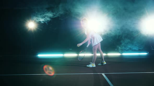 Athletic Lady is Serving a Tennis Ball in a Dark Hall alt