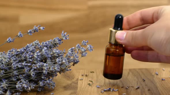 Lavender Oil. Close-up of lavender extract droplets falling from a glass pipette. alt