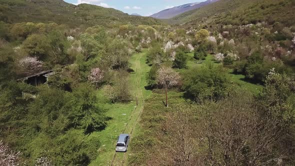 Aerial View of Silver Car Driving on Country Road in Abandoned Mountain Village