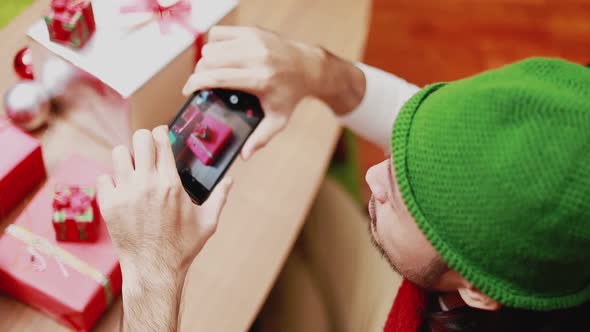 Asian men taking a photo gift box on smartphone decorate Christmas tree celebrates the new year.