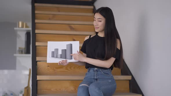 Portrait of Young Confident Asian Woman Posing with Business Graph in Home Office alt