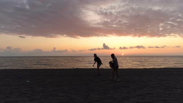 Anonymous Women Cleaning Beach In Evening