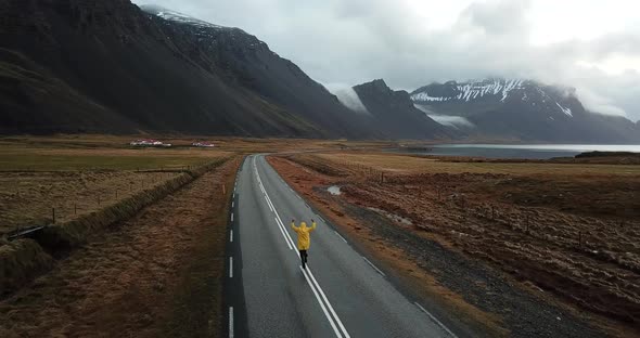 Aerial shot of happy man running on empty road in Iceland alt