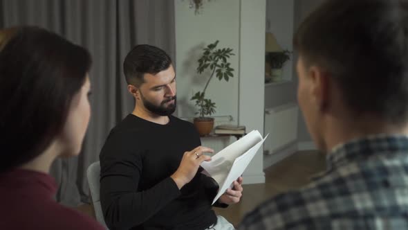 Portrait of Young Psychologist with Black Hair Showing Patients Rorschach Inkblots alt