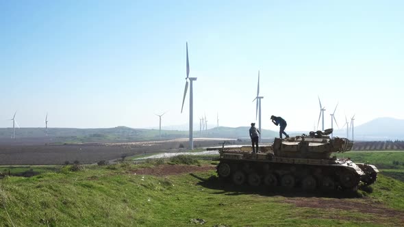 father and son standing on a tank with wind turbines in the background 4k