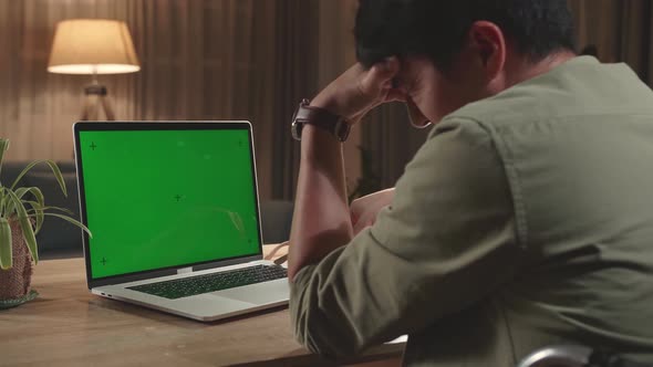 Upset Asian Man Sitting In A Wheelchair While Working On Mock Up Green Screen Laptop Computer alt