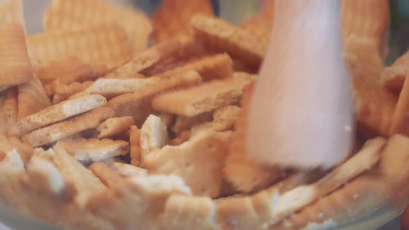 Cookies Are Crushed Into Crumbs in a Glass Bowl with a Pestle - Closeup alt