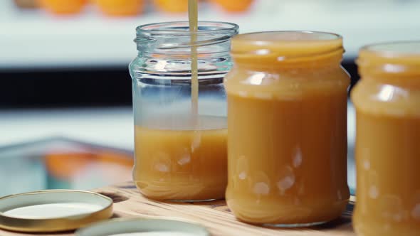 Hot Liquid Salted Caramel is Poured in a Thin Stream Into a Transparent Jar to the Very Edge alt