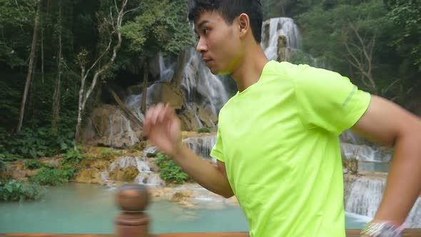 Asian Man Running, Waterfall at the Background alt