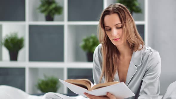 Relaxed Domestic Young Woman in Pajamas Reading Book Turning Page alt