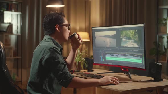 Asian Male Video Editor Works And Drinking Coffee With His Personal Computer alt