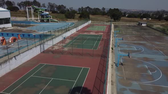 A drone shot of old, red and green tennis courts in an apartment complex. Shot in the summer during alt