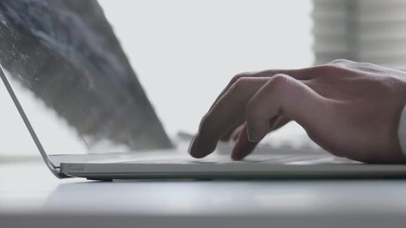 Extreme close-up of hand businessman typing on the keyboard working on a laptop in the office.