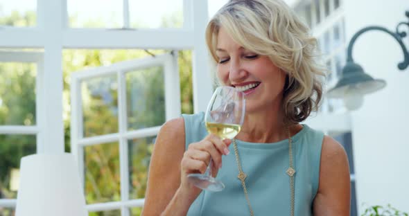 Woman interacting while having glass of wine in restaurant alt