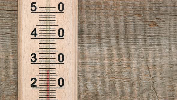 Increasing temperature on wooden thermometer with red scale alt