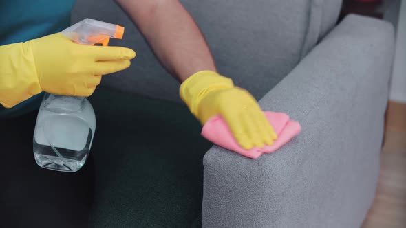 A man cleans a sofa with a rag, close-up