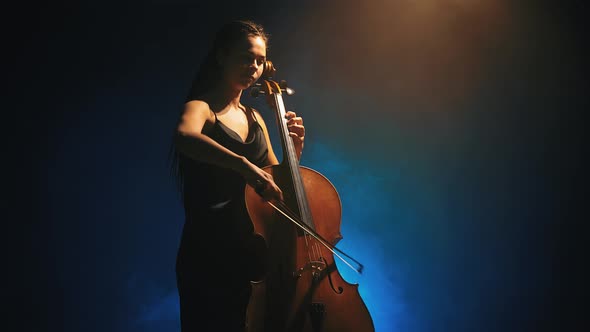Young Beautiful Woman Playing a Melody on Cello. Smoky Dark Studio