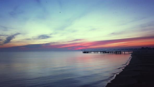 Early morning on the beach just before the sunrise. Drone footage. Orange and purple sky. Relaxing s alt